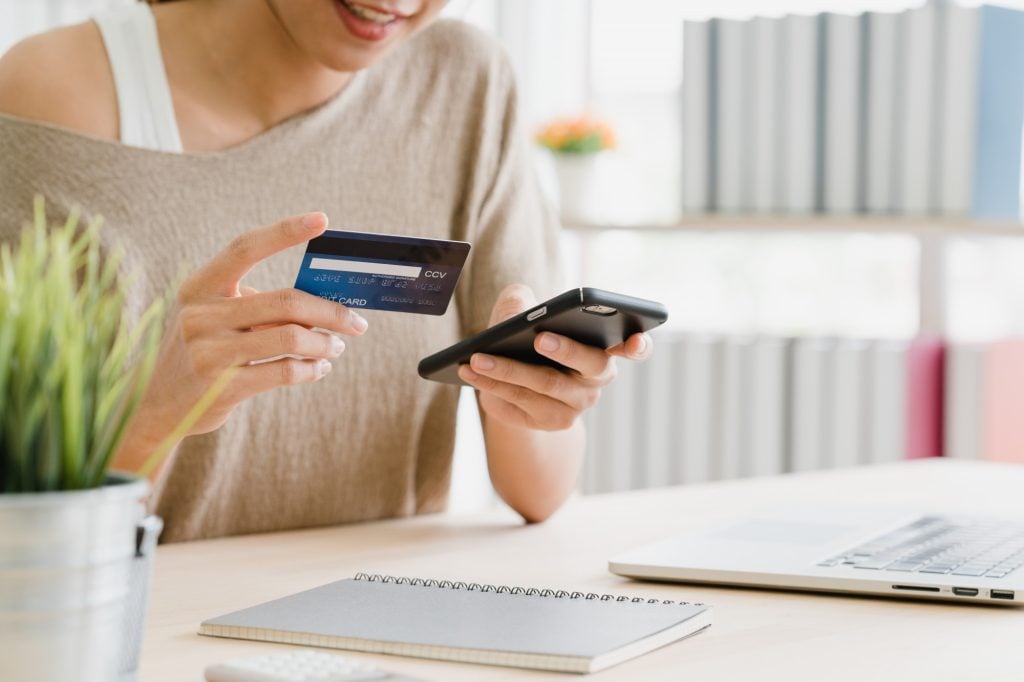 woman using smartphone and holding credit card