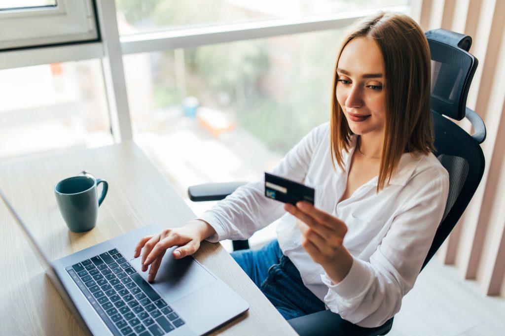 woman holding credit card using lap top